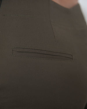 Asymmetrical low waist kick-flare trousers in olive green cotton gabardine. Inseam slit with zip fastening.