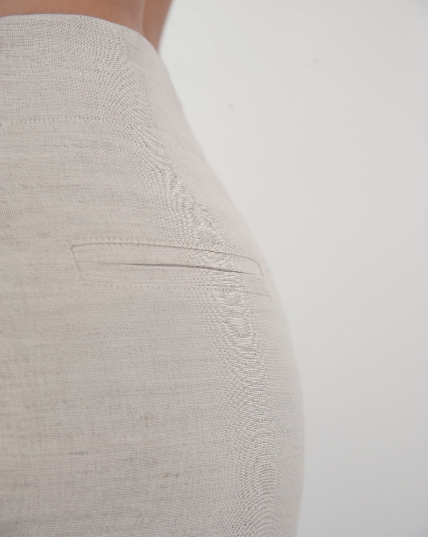Dipped low waist kick-flare trousers in nude linen. Inseam slit with zip fastening.