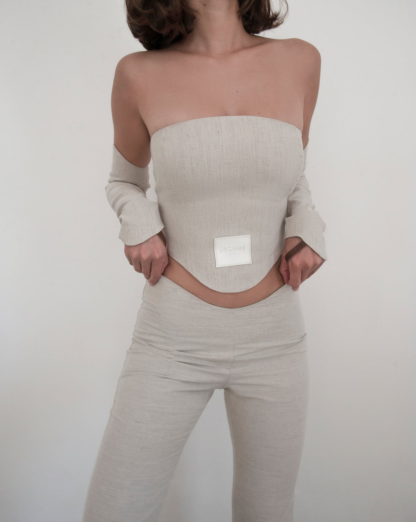 Dipped low waist kick-flare trousers in nude linen. Inseam slit with zip fastening.