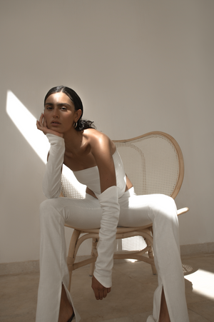 Dipped low waist kick-flare trousers in white linen. Inseam slit with zip fastening.