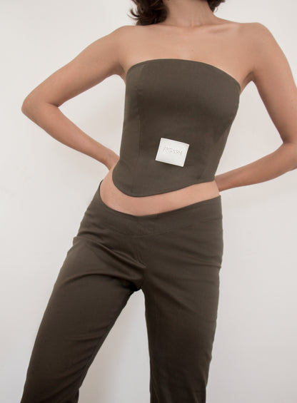 Asymmetrical low waist kick-flare trousers in olive green cotton gabardine. Inseam slit with zip fastening.